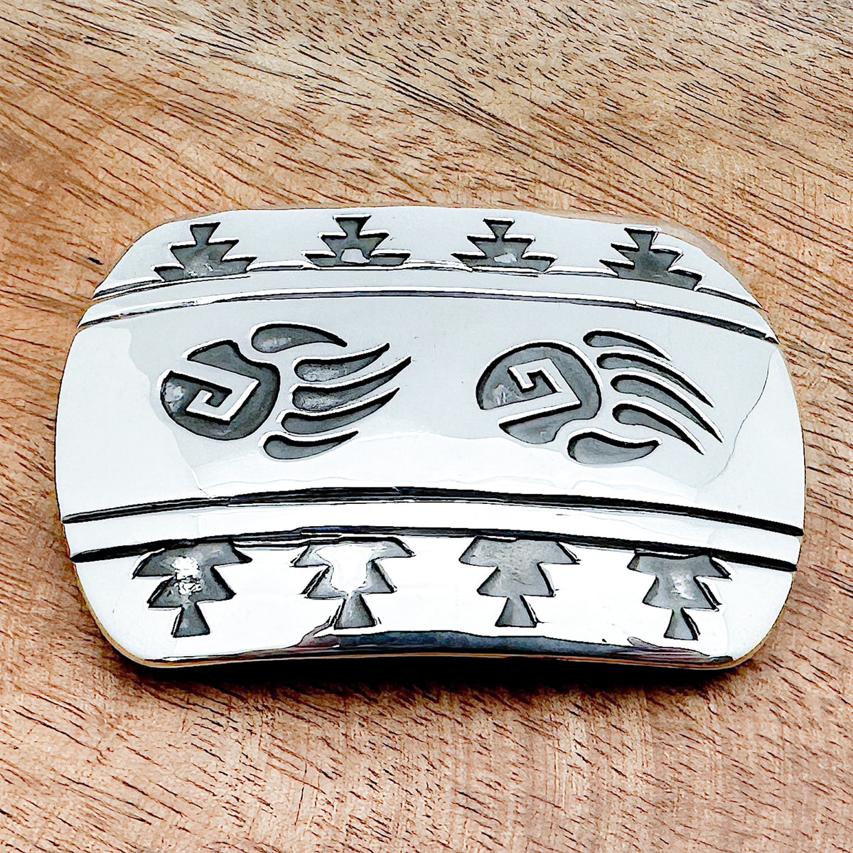 Silver belt buckle with bear paws etched into it