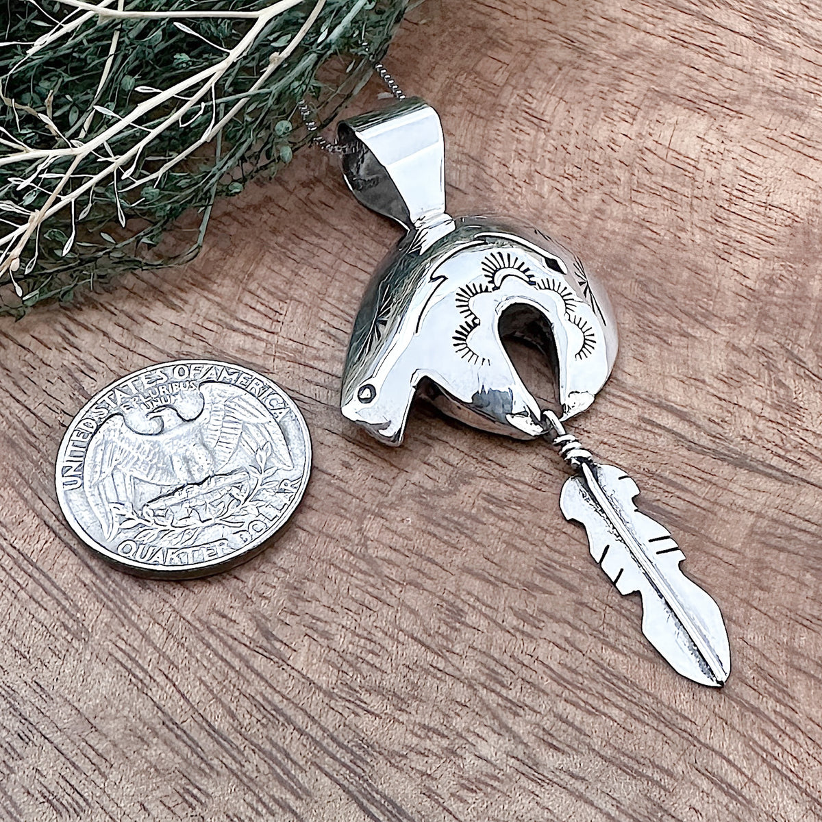 Comparison shot of a US quarter coin and a pendant that is shaped like a bear and feather