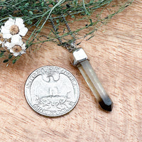 Comparison shot of a US quarter coin and a pendant with a citrine point