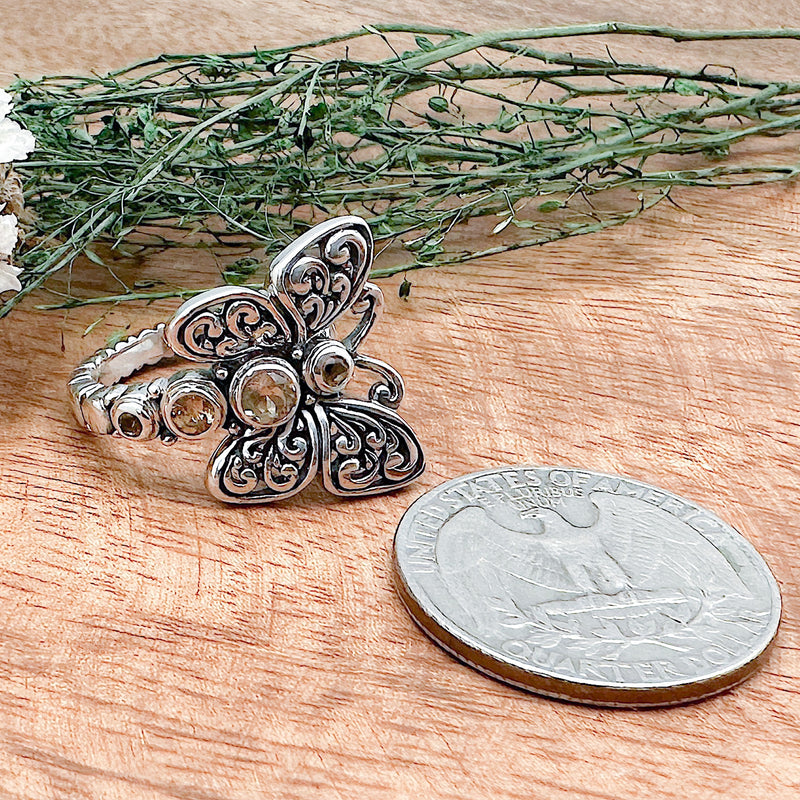 Comparison shot of a US quarter coin and a citrine ring with a butterfly design