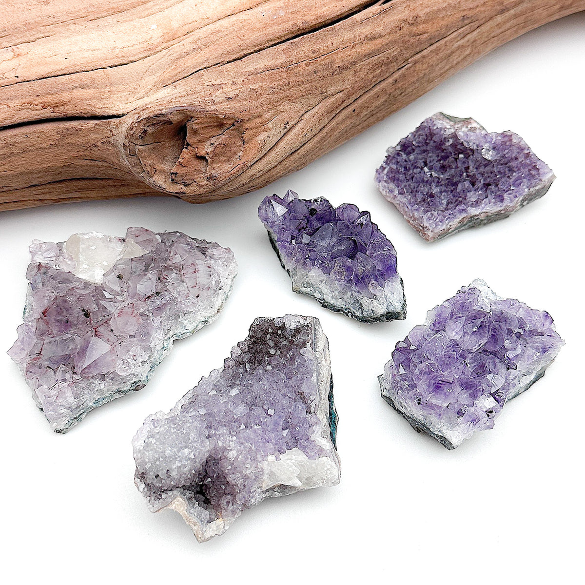 Amethyst geode clusters of various sizes and hues laid together on a white background