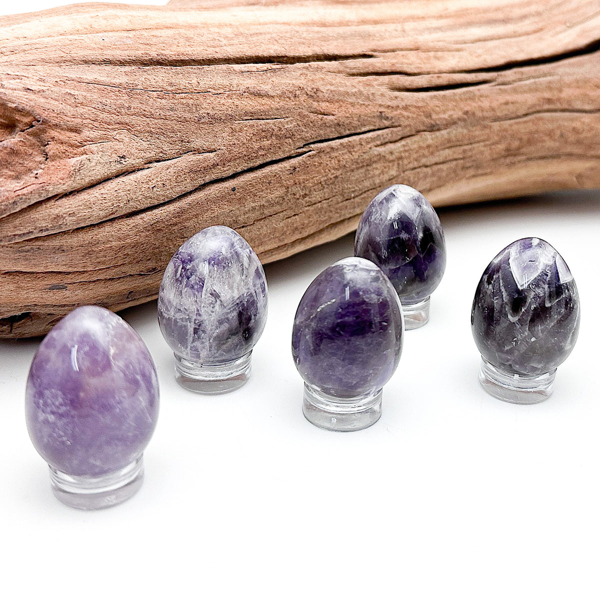 Amethyst eggs of various hues and patterns laid out together on a white background
