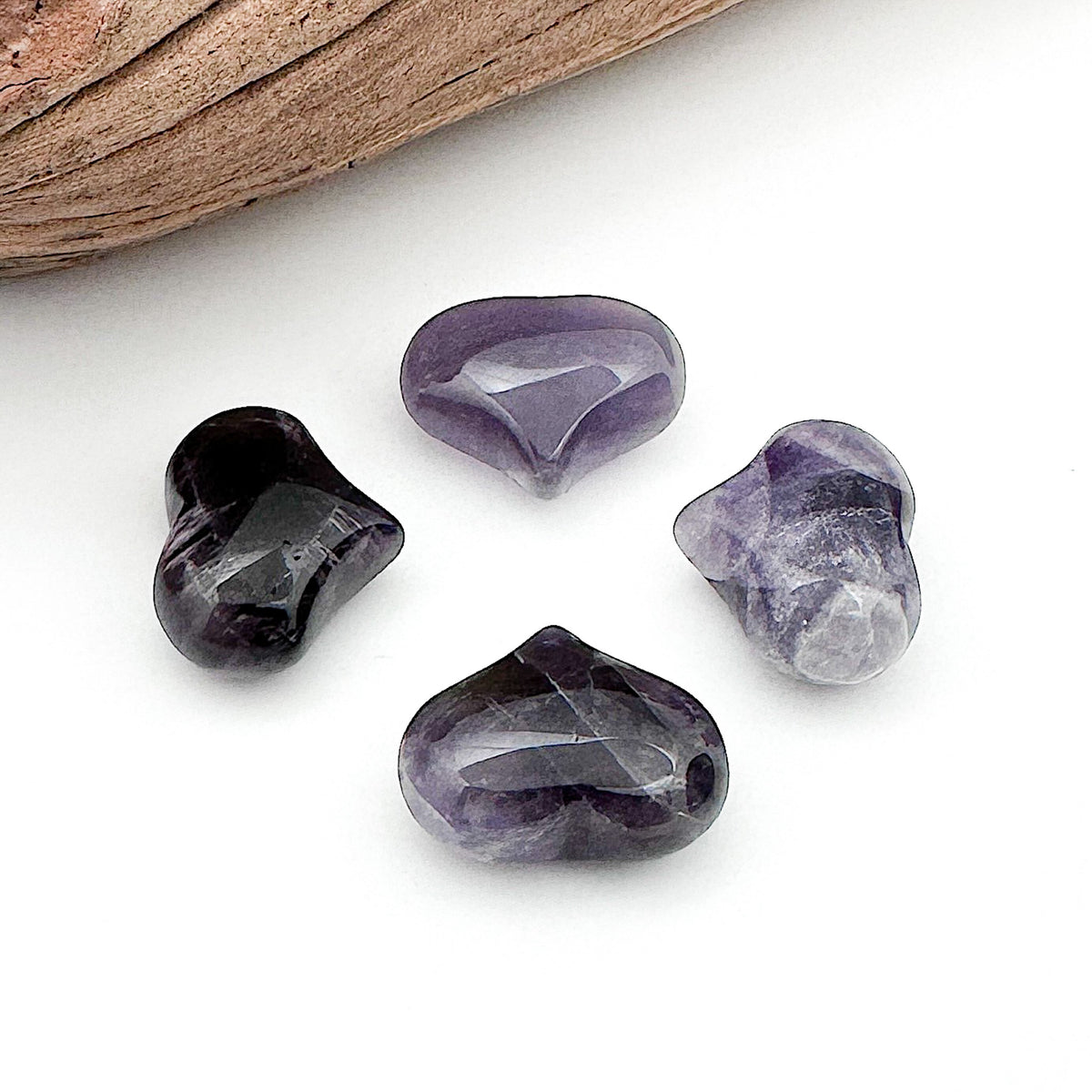 Four amethyst hearts laid out so the ends all point towards the center of the group
