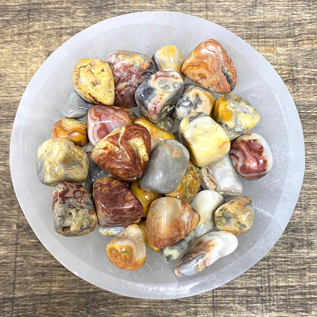 Overhead shot of various Crazy Lace Agate tumbled stones in a small bowl.