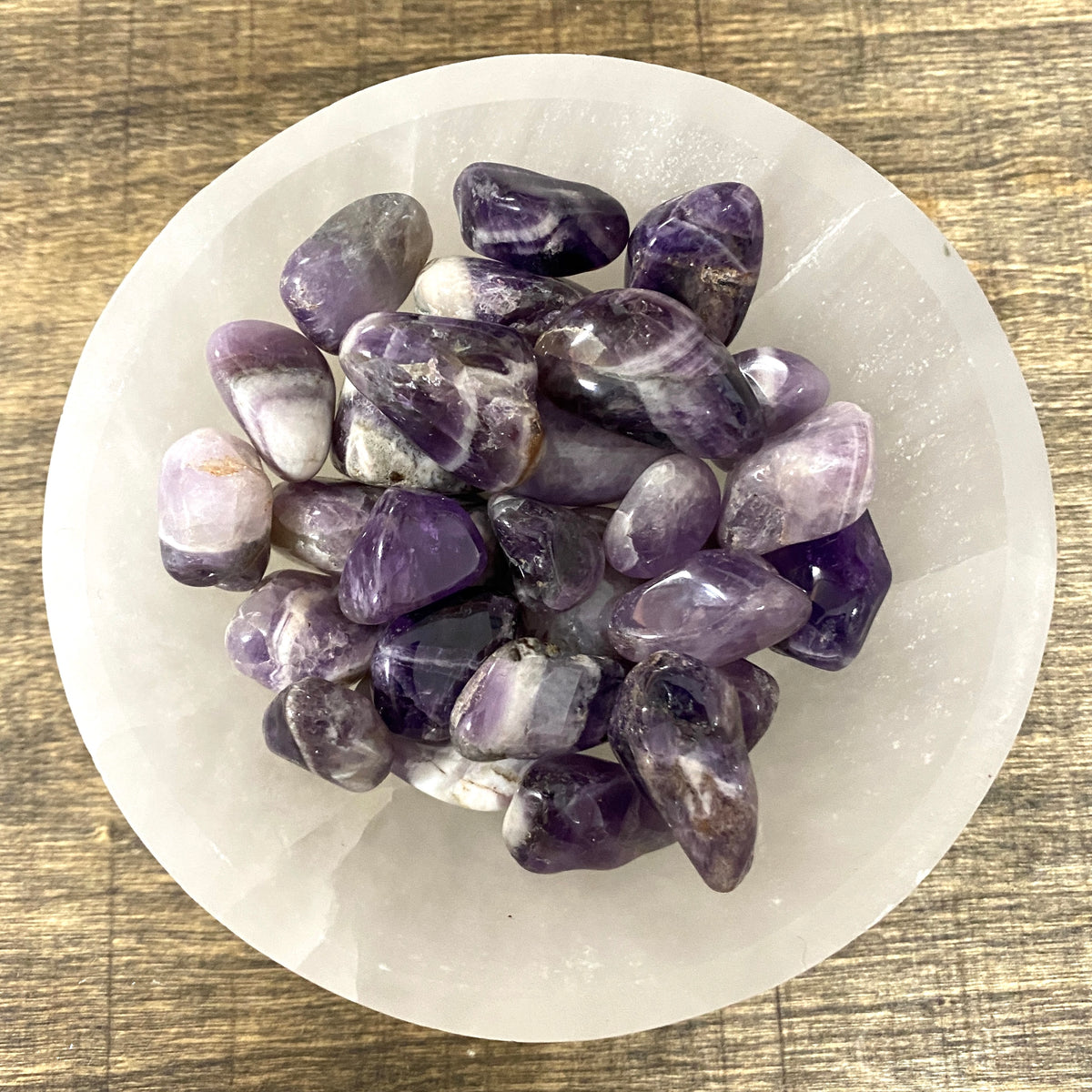 Overhead shot of various Chevron Amethyst tumbled stones in a small bowl.
