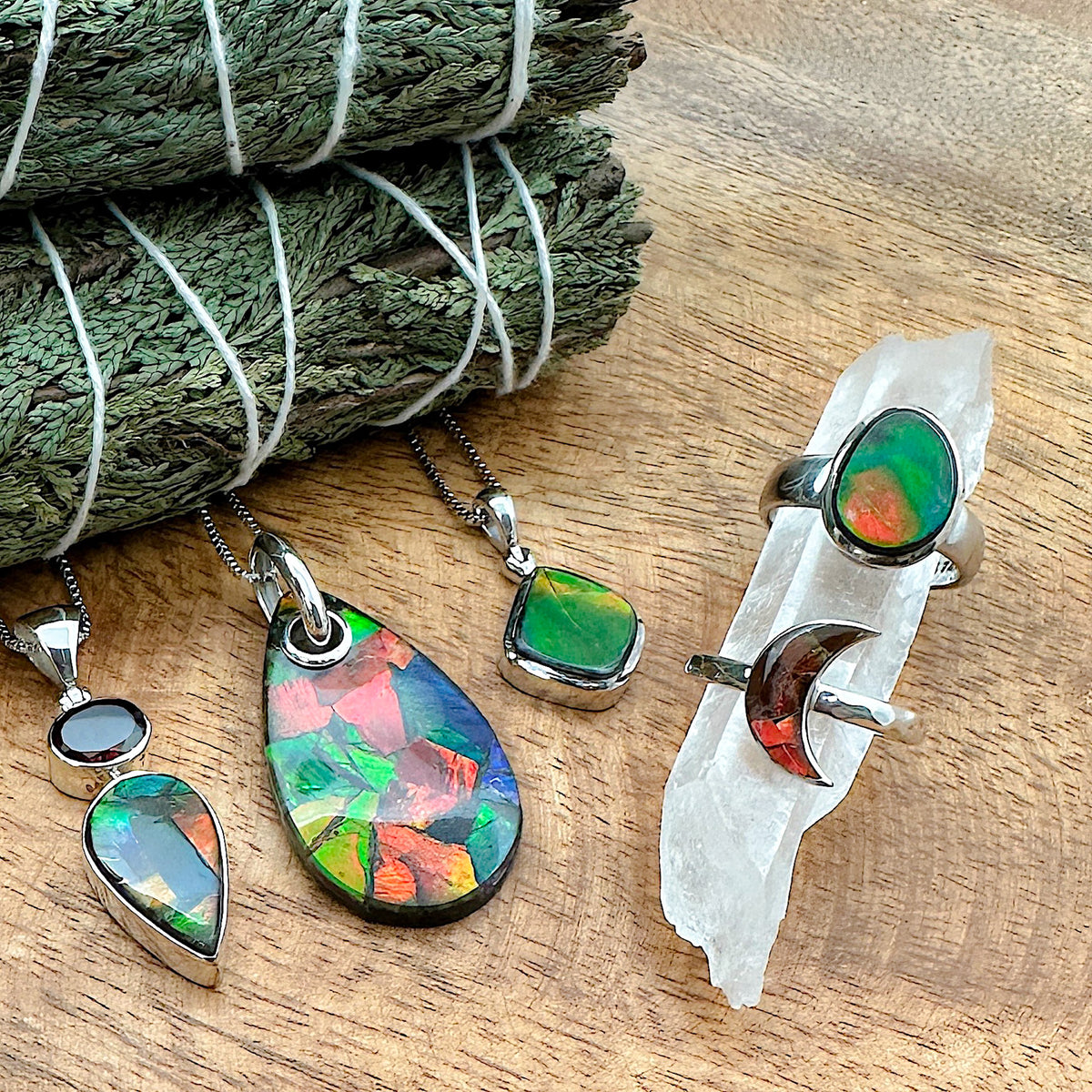 Various pieces of Ammolite jewelry laid out together against a wood background