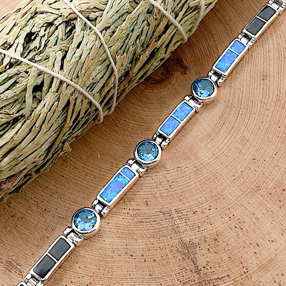 A sterling silver bracelet that is inlaid with Black Jade, Blue Cultured Opal, and is set with three London Blue Topaz stones laid flat