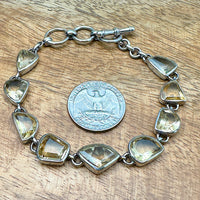 Comparison shot of a US quarter coin and a bracelet with multiple citrine stones