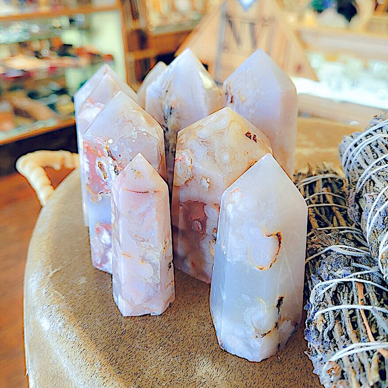 Shot of multiple cherry blossom agate points grouped together next to a decorate bundle of herbs