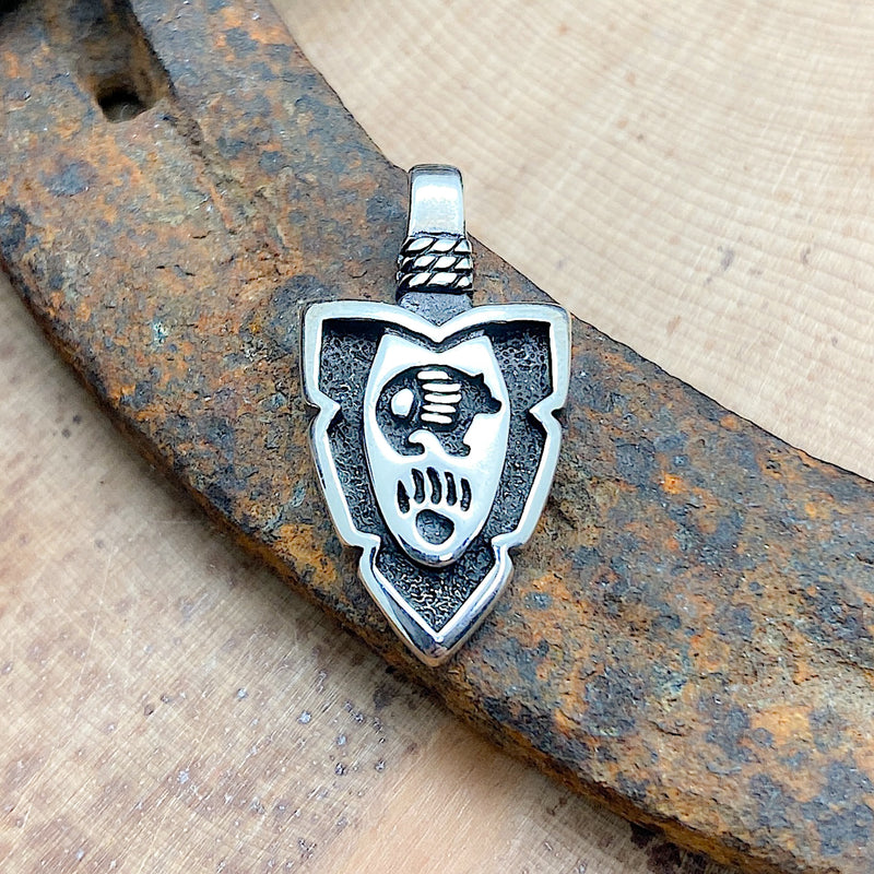 An arrowhead pendant with a bear and bear paw etched into the pendant