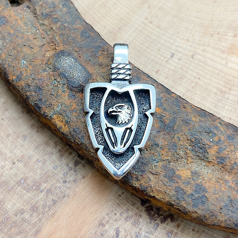 An arrowhead with the head of an eagle and feathers etched into the pendant
