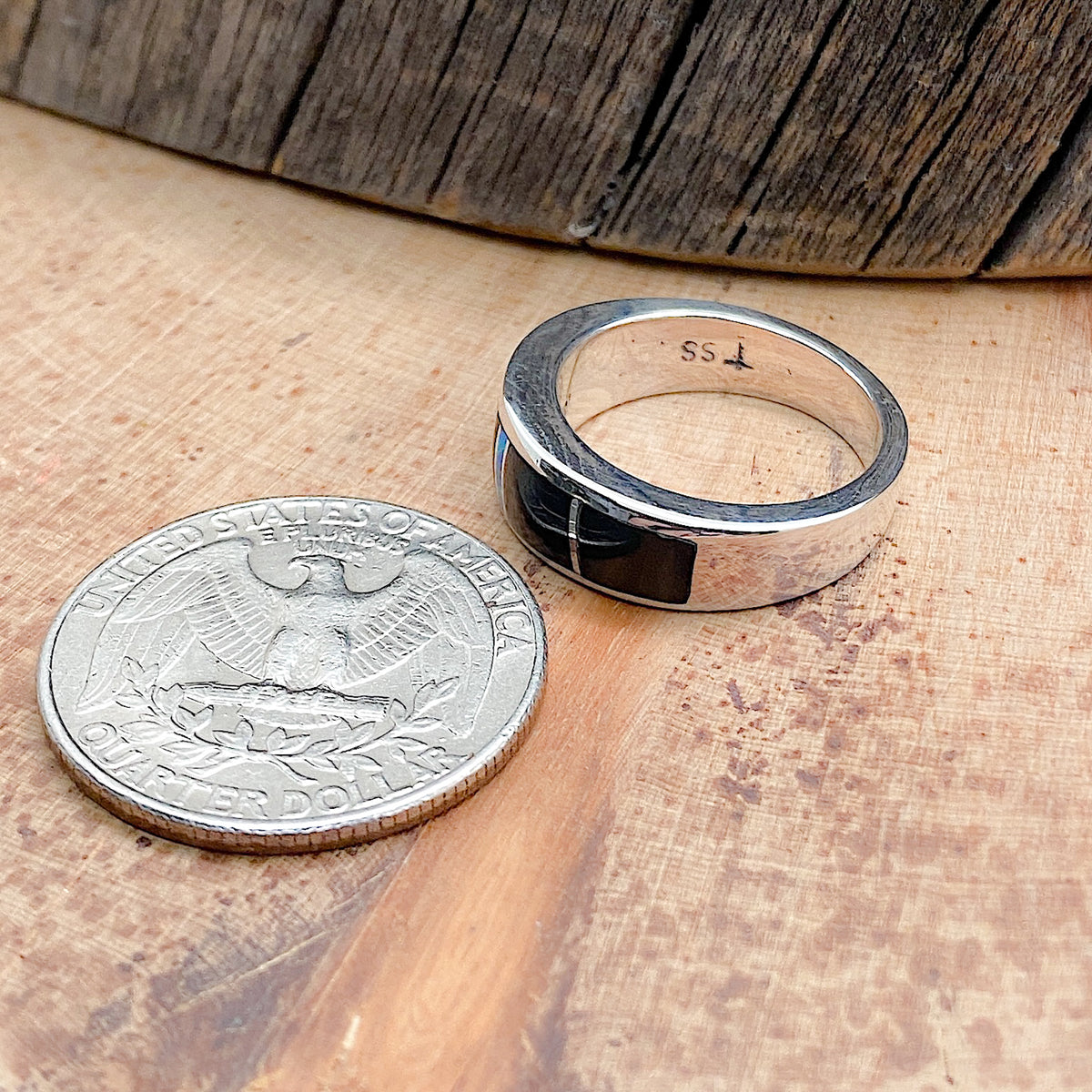 Comparison shot of a US quarter coin and Silver ring with several varieties of stones inlaid into the top. The silver ring is shown from the side.