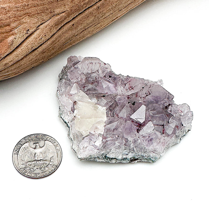 A comparison shot of a US quarter coin and an amethyst cluster