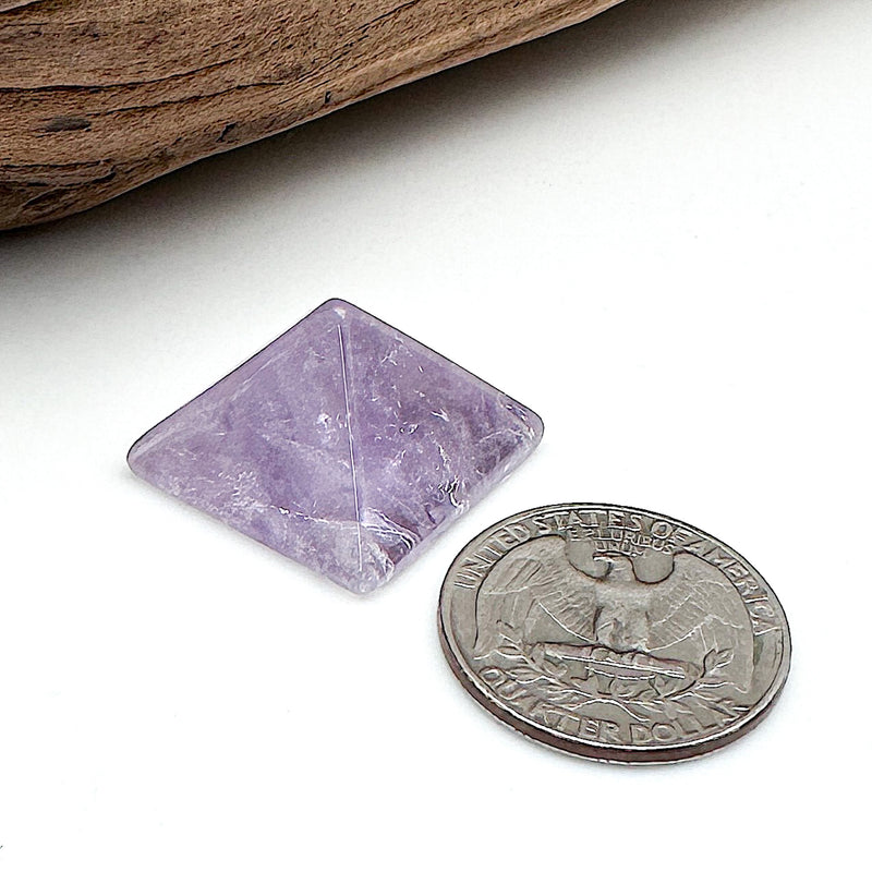 A comparison shot of an amethyst pyramid and a US quarter coin