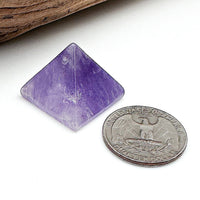 A comparison shot of an amethyst pyramid and a US quarter coin