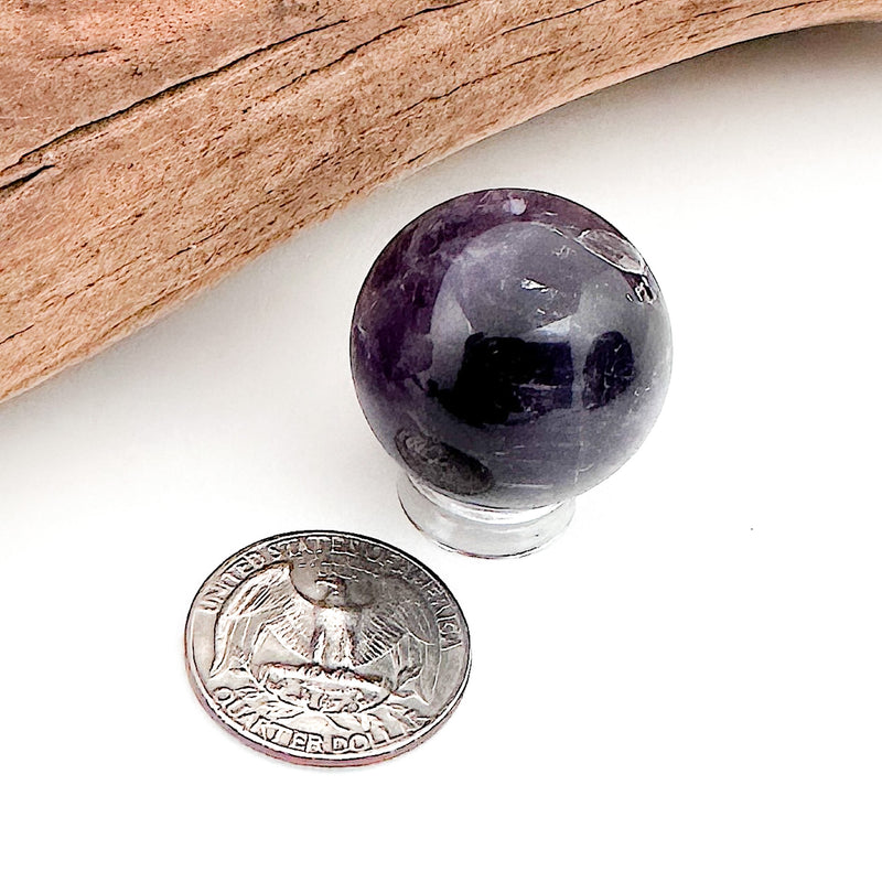 A comparison shot of an amethyst sphere and a US quarter coin