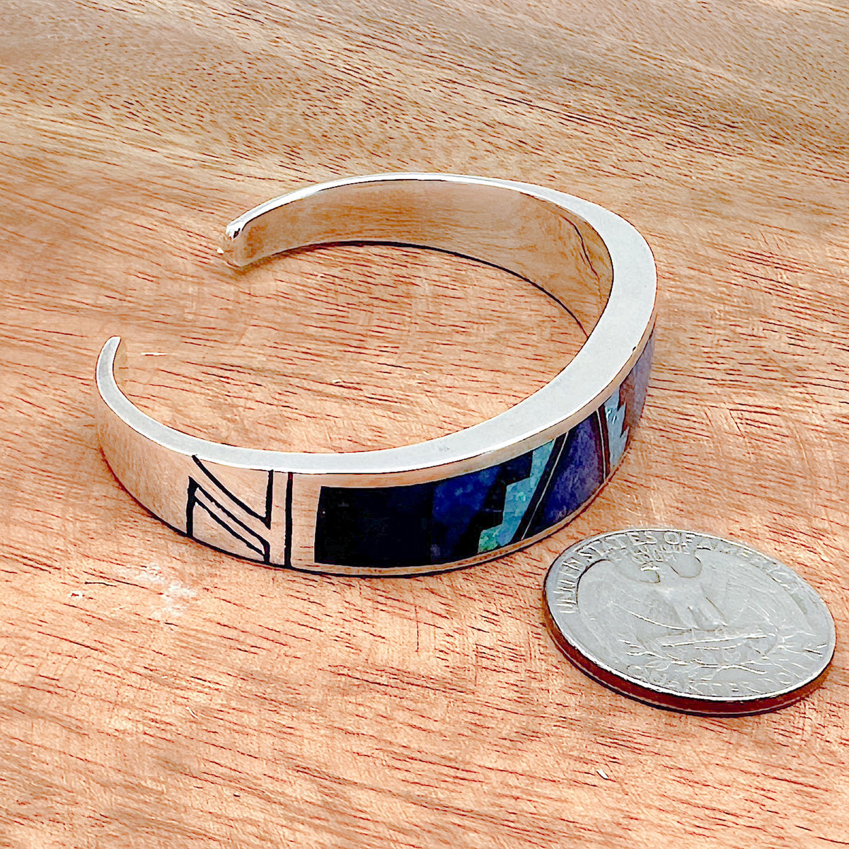 Comparison shot of a US quarter coin and a blue sky inlay cuff bracelet as viewed from the side