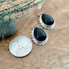 Comparison shot of a black onyx tear drop earrings and a US quarter coin