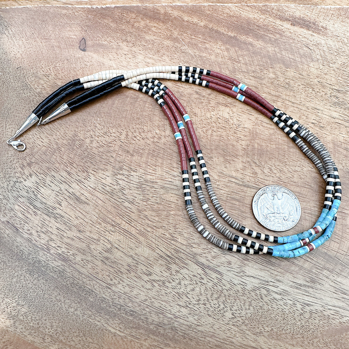 Size comparison of a US quarter coin and a handmade three strand Heishi necklace that features a variety of stones and shells with sterling silver findings.