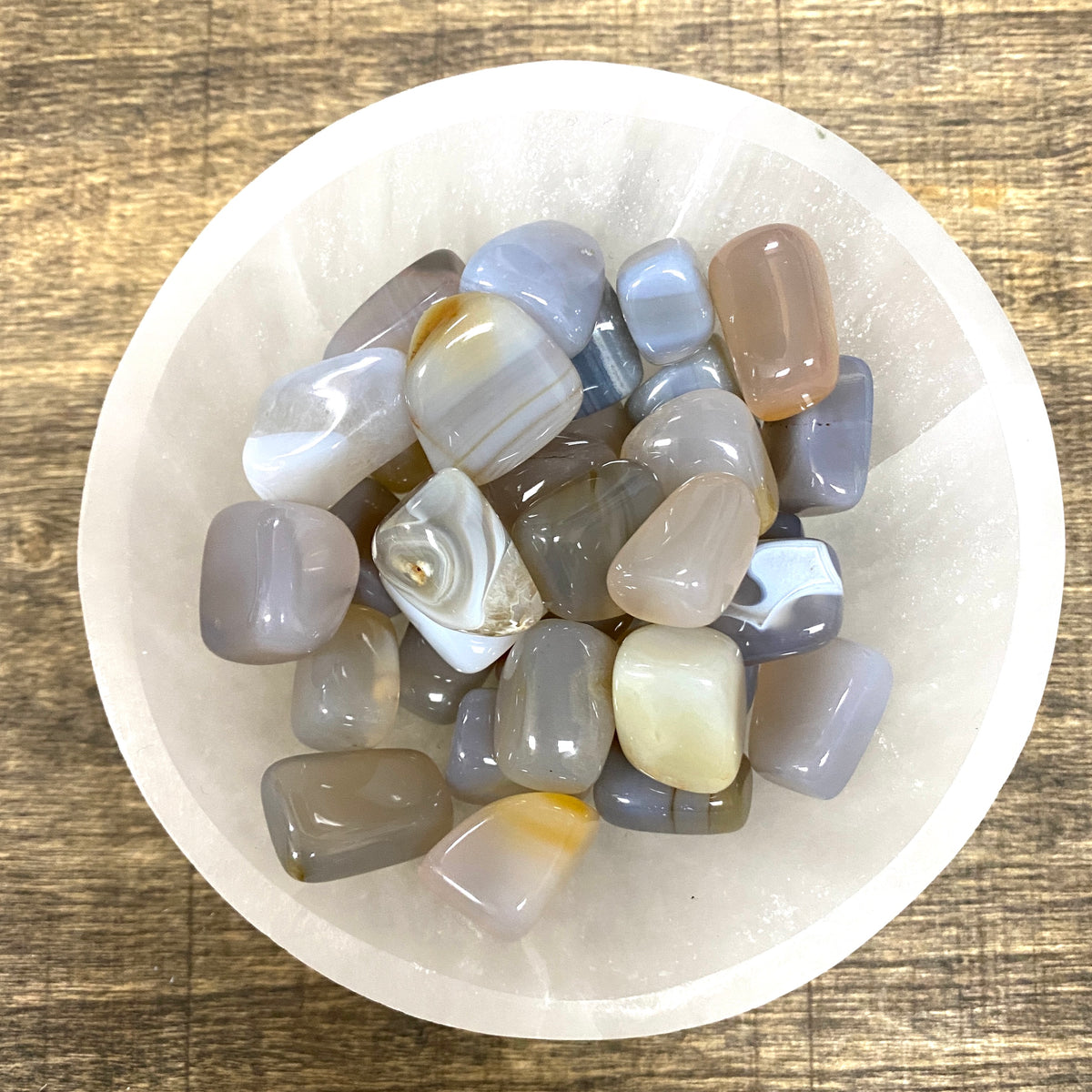 Overhead shot of various Agate tumbled stones in a small bowl.