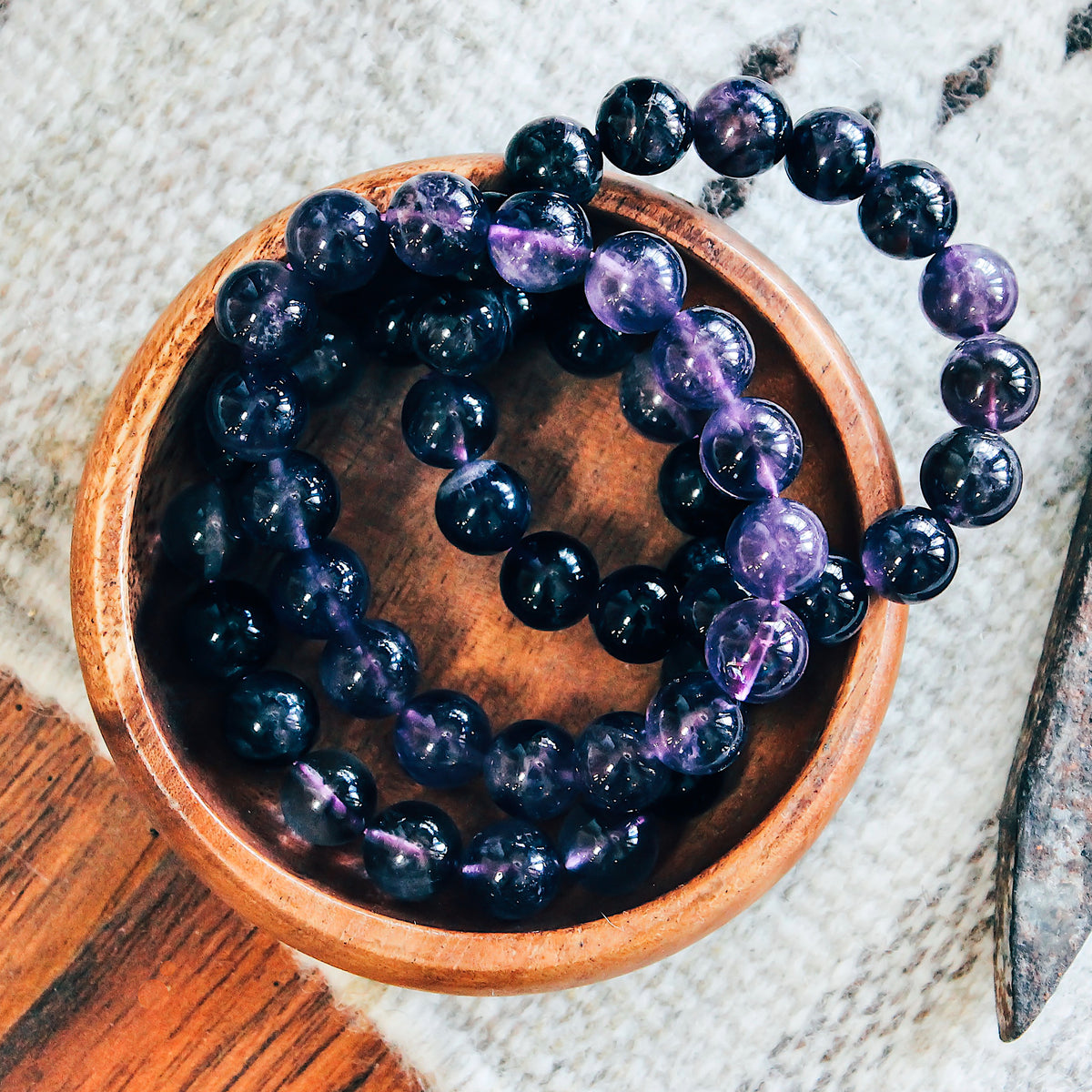 Multiple amethyst beaded bracelets placed in a small wooden container