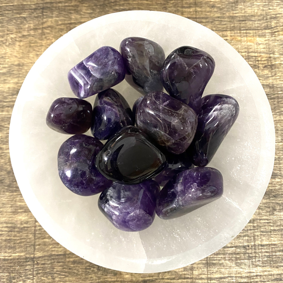 Overhead shot of various Amethyst tumbled stones in a small bowl.