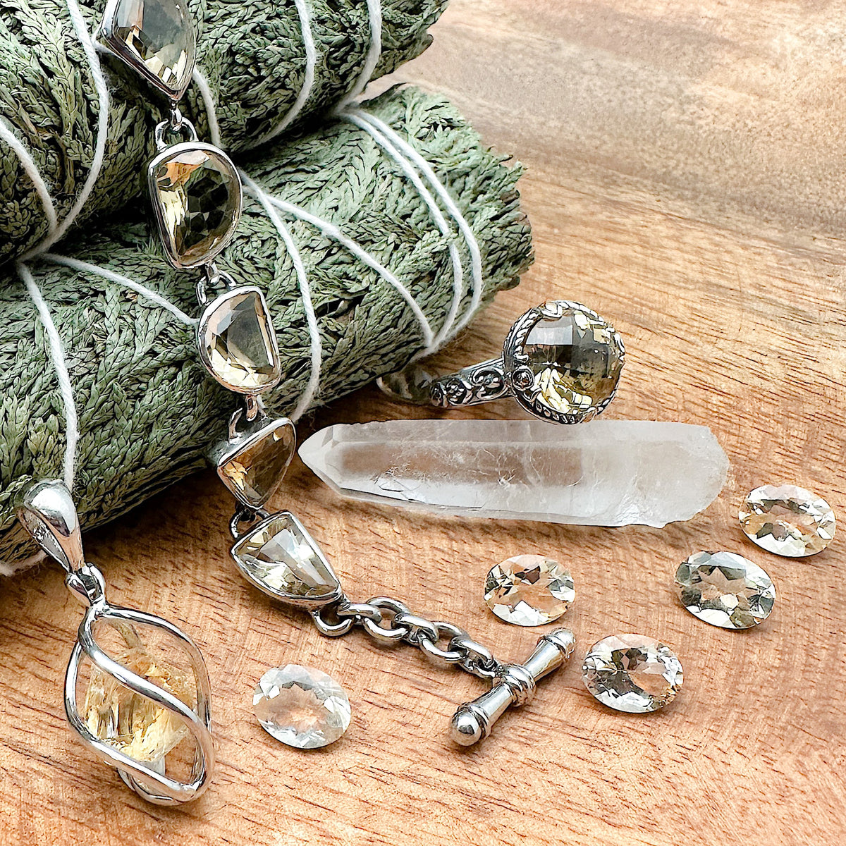 Shot of various different pieces of Citrine jewelry placed together. It includes a citrine pendant, a citrine bracelet, a citrine ring and multiple decorative stones