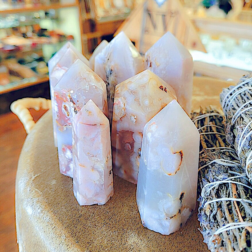 Shot of multiple cherry blossom agate points grouped together next to a decorate bundle of herbs