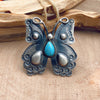 Shot of a sterling silver ring in the shape of an ornate butterfly with a teardrop-shaped turquoise stone embedded into the front of the ring