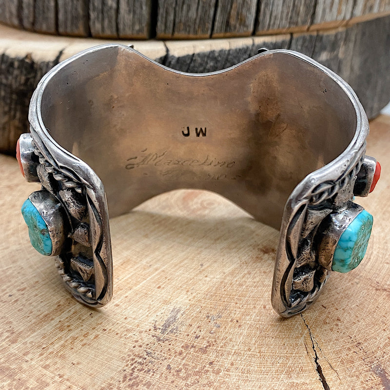 Back side view of a large Native handmade sterling silver vintage watch cuff with natural sleeping beauty nugget turquoise and natural Mediterranean Red Coral set into the bracelet.